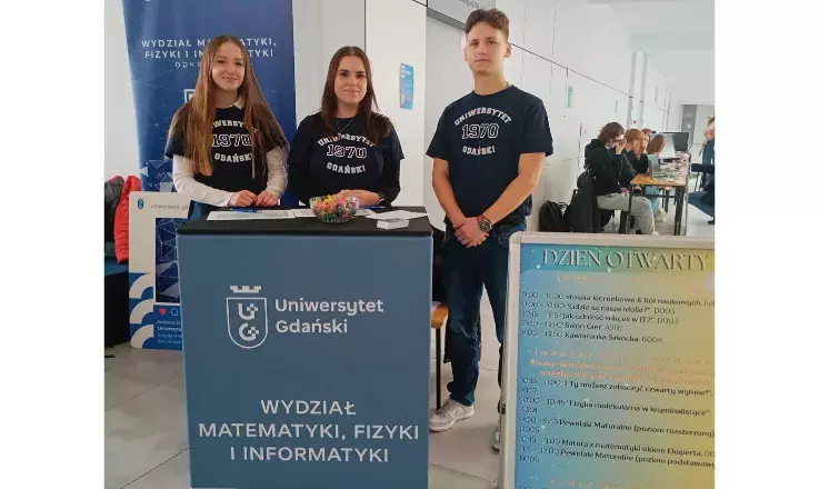 troje studentów przy stoisku informacyjnym podczas dnia otwartego 