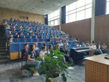uczestnicy z przodu, publiczność w tle na auli
