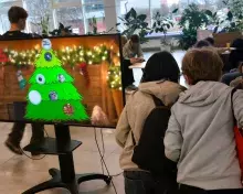 stoisko KN Work In Progress i uczniowie tworzący cyfrowe bombki